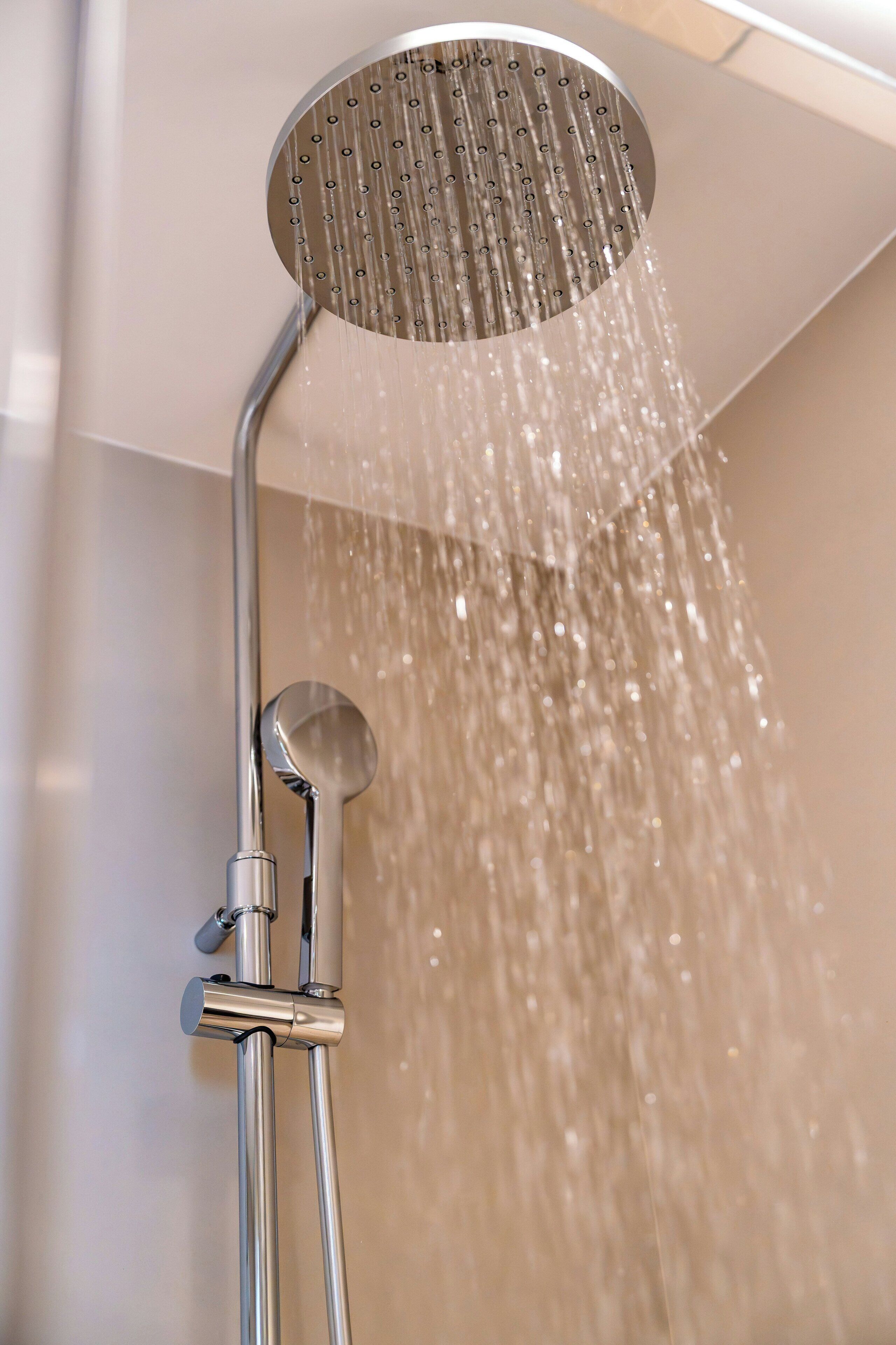 A showerhead with water flowing down, part of a bathroom fixture.