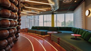 Un'area lounge moderna con un pavimento in legno curvo, sedute verdi e una parete di palloni da calcio in pelle.