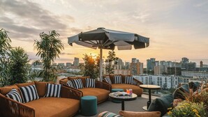 Um terraço com área de estar, incluindo sofá, mesa redonda e guarda-sol.