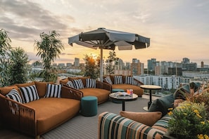 Eine Dachterrasse mit einer Sofagarnitur, einem runden Tisch und einem Sonnenschirm.