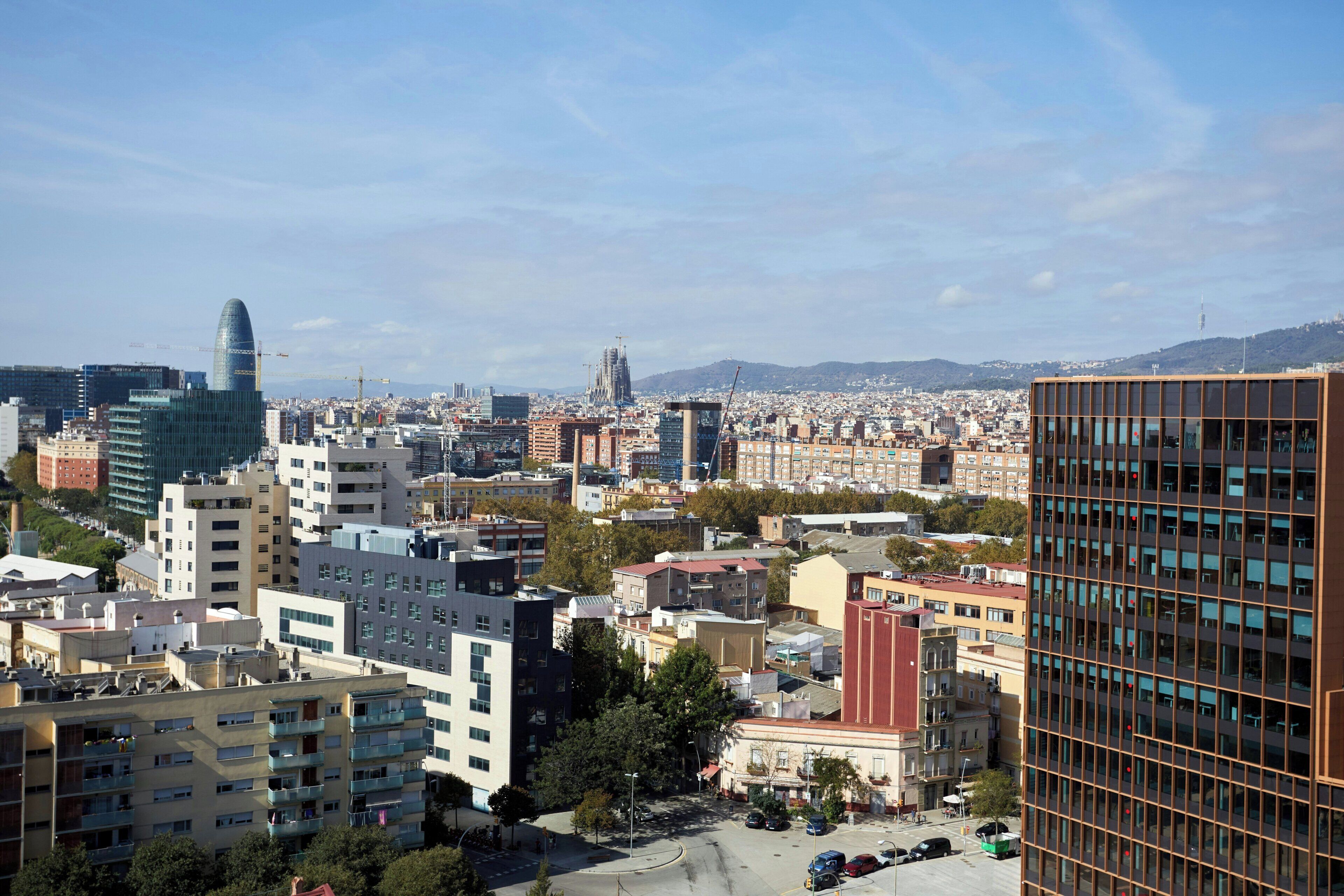 A cityscape with modern buildings, a prominent glass skyscraper, and a mix of residential and commercial structures.