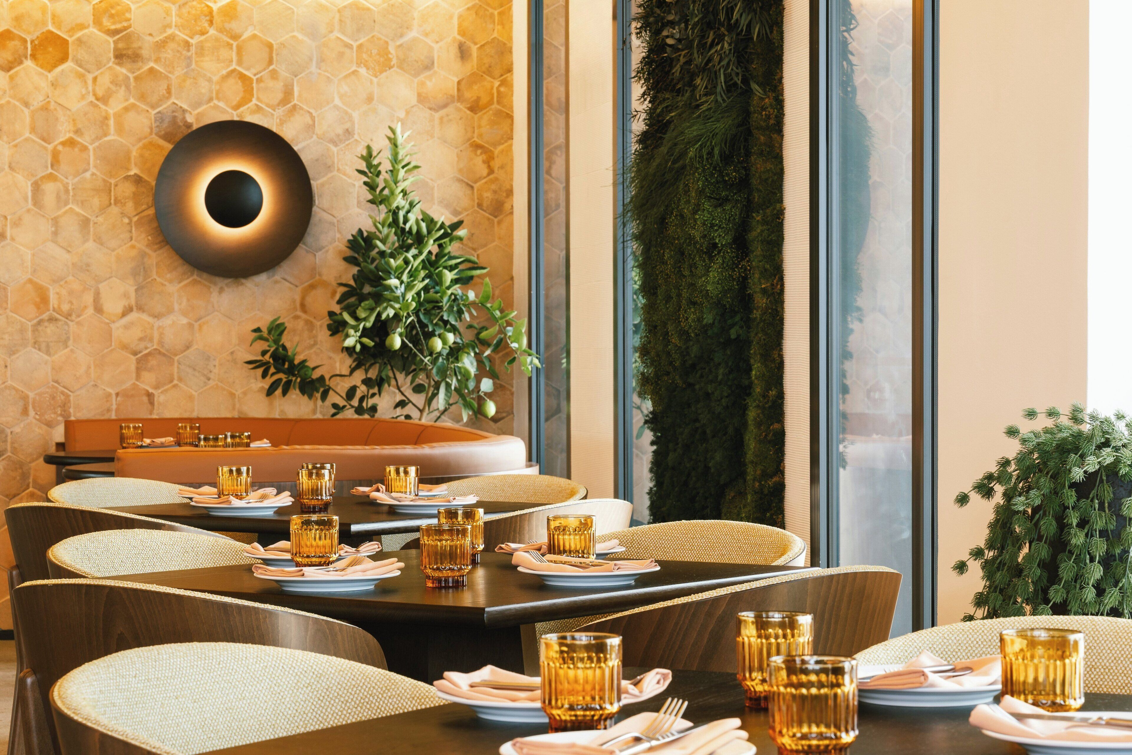 Un comedor con paredes de baldosas hexagonales, una lámpara de pared redonda y un jardín vertical verde.