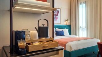 Habitación de hotel con una cama, un escritorio con cafetera, un hervidor y una taza de café.