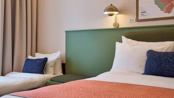 A hotel room with two beds, a green headboard, a map on the wall, and a lamp.
