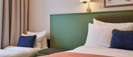A hotel room with two beds, a green headboard, a map on the wall, and a lamp.