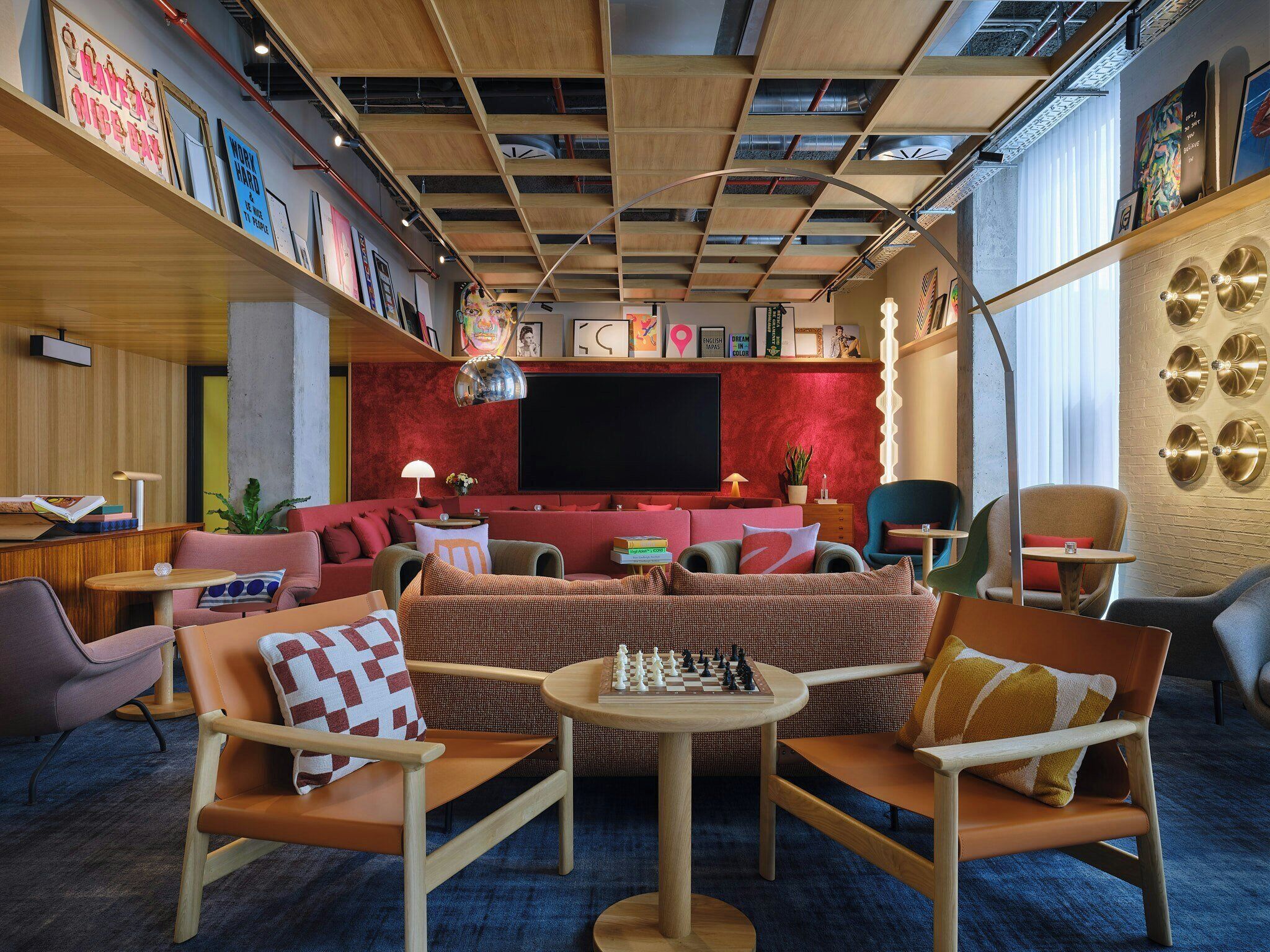 Un espace de détente moderne doté d’un grand téléviseur à écran plat, de sièges confortables et d’une bibliothèque contenant divers objets.