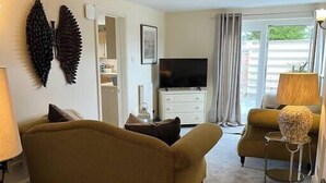 A living room with a sofa, a TV, a lamp, and a decorative wall piece. - Cosy Wrekin View Annexe (Eaton Constantine)