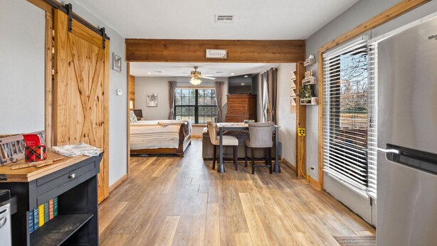 A modern kitchen with a dining area, wooden flooring, and a large window with blinds. - Cozy Hideaway in Denison Tx (Denison)