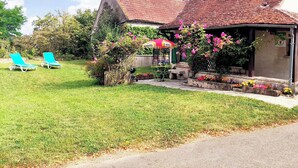 A house with a tiled roof, a garden with a lawn, and a small outdoor seating area with a table and chairs. - ''le Cocon'' (Tracy-sur-Loire)