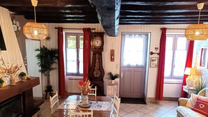 A dining area with a wooden table and chairs, a clock, and a door leading to another room. - ''le Cocon'' (Tracy-sur-Loire)