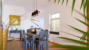 A dining area with a wooden table, blue chairs, and a vase of dried branches.