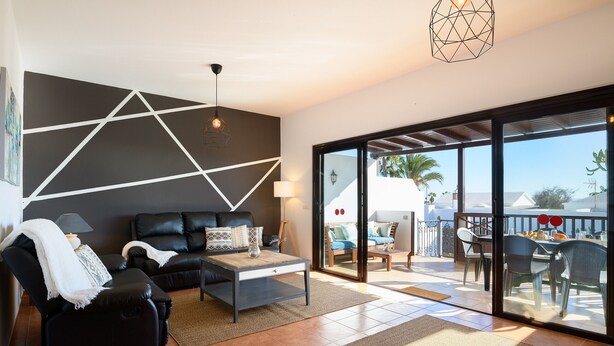 A modern living room with a black leather sofa, a coffee table, and a dining area with a table and chairs.