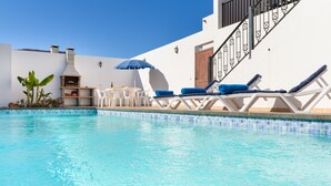 A swimming pool with lounge chairs and a barbecue area.