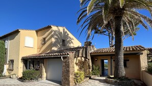 A Mediterranean-style building with a tiled roof, stone walls, and a palm tree.