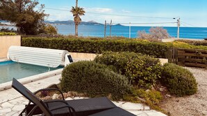 A pool area with lounge chairs, a palm tree, and a view of the sea. - Beach house with pool in Les Issambres 4****, 40 meters  sea Plage La Gaillarde (Roquebrune-sur-Argens)