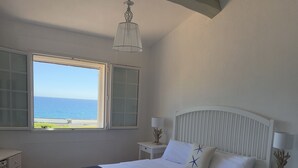 A bedroom with a bed, two bedside tables, a nightstand, a window with a view of the sea, and a hanging light fixture. - Beach house with pool in Les Issambres 4****, 40 meters  sea Plage La Gaillarde (Roquebrune-sur-Argens)