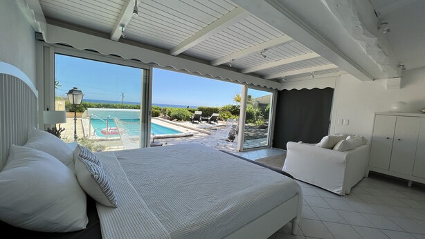 A bedroom with a large bed, a view of a swimming pool, and a balcony. - Beach house with pool in Les Issambres 4****, 40 meters  sea Plage La Gaillarde (Roquebrune-sur-Argens)