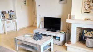 En stue med sofa, sofabord, fjernsyn og pejs.