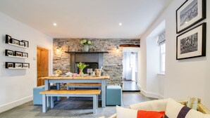 A cozy living room with a stone wall, a wooden bench, a dining table, and a sofa with a cushion. - A beautiful renovated Georgian house minutes walk to Port Isaac's harbourside (Port Isaac)