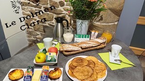 Una mesa de desayuno con una variedad de alimentos, como pan, bollería, frutas y bebidas.