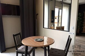 Ett rum med ett runt träbord, två stolar, en spegel och utsikt över ett köksområde.