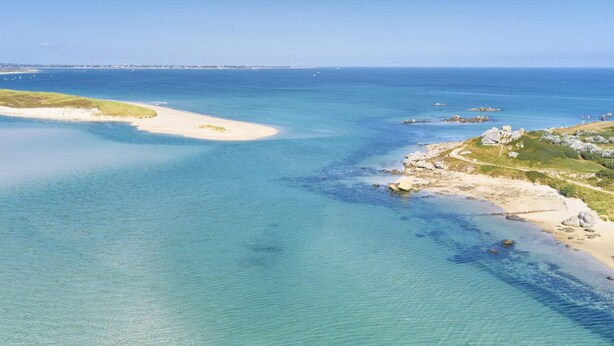 Vista aérea de una zona costera con aguas azul turquesa, playas arenosas y afloramientos rocosos.