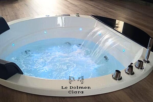 Ett bubbelbad med vattenstrålar, en kontrollpanel och texten ”Le Dolmen Clara” på sidan.