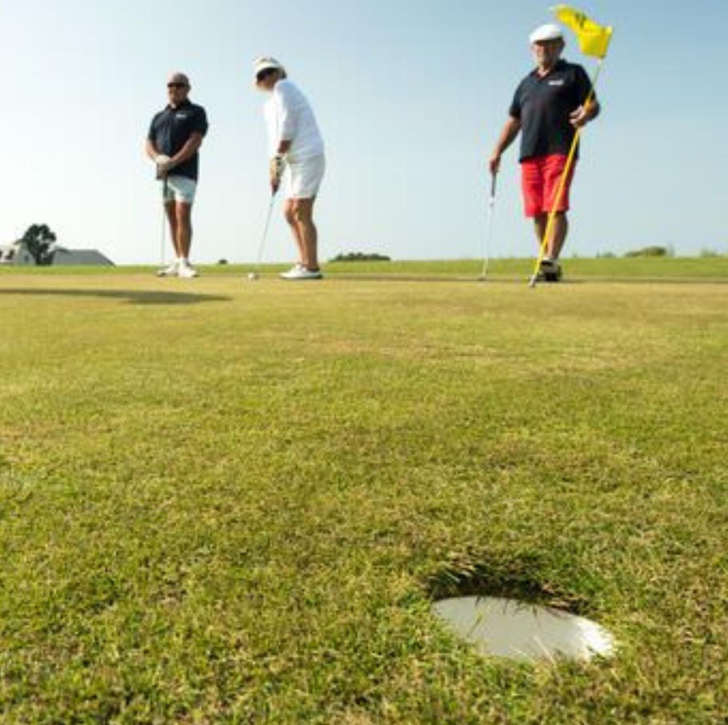 A golf course with players and a golf ball on the green.