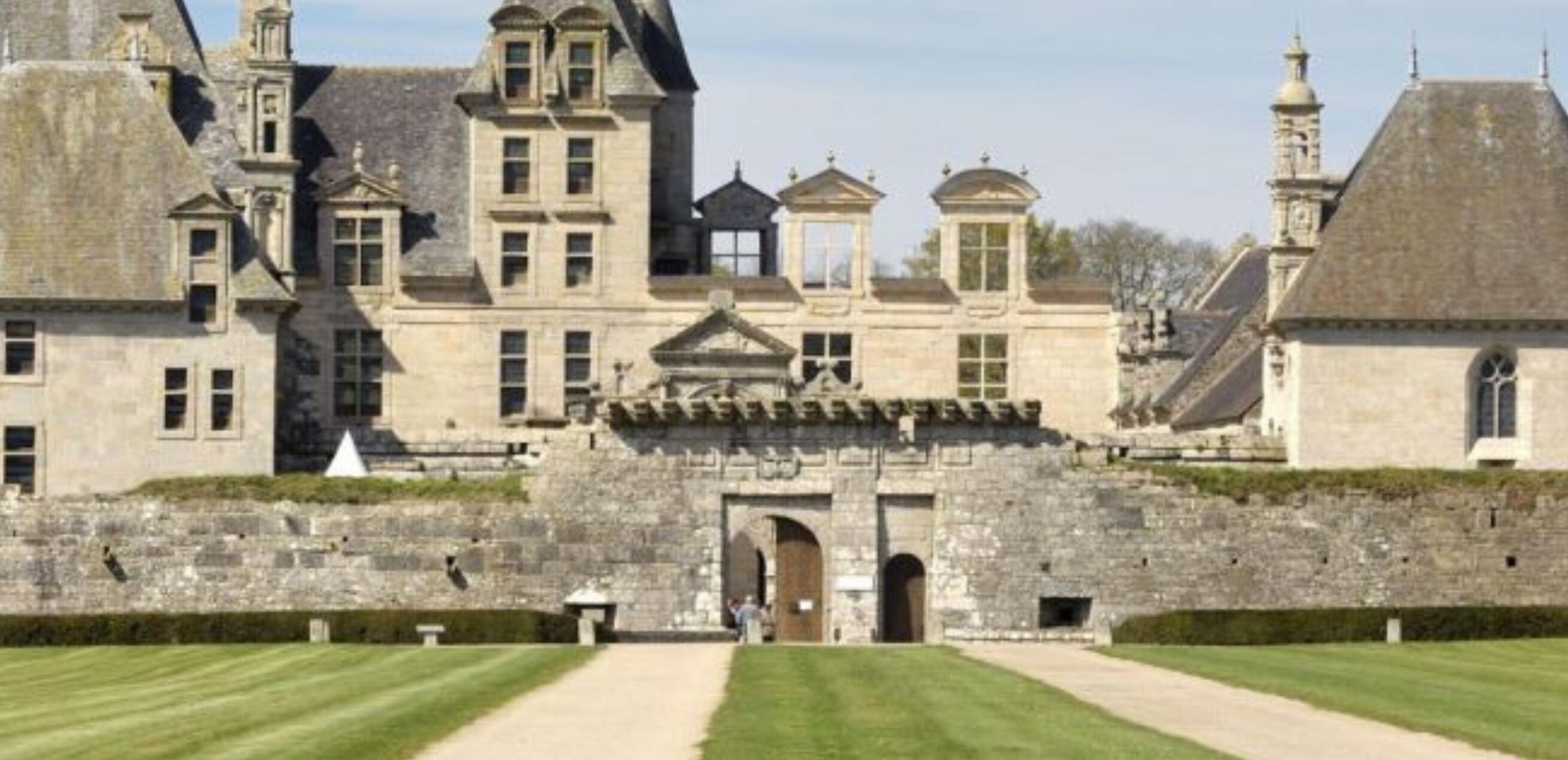 A large, historic stone building with multiple towers and a central entrance.
