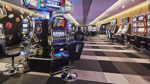 Un casino con múltiples máquinas tragamonedas, taburetes de bar y un suelo a cuadros.