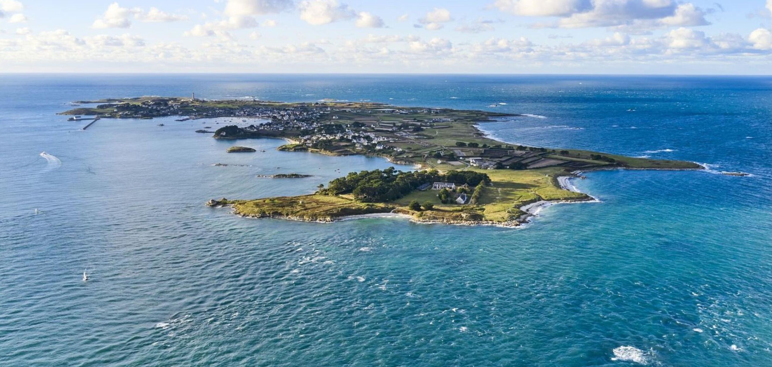 An aerial view of a coastal area with multiple islands, including a prominent island with a lighthouse and a cluster of buildings.