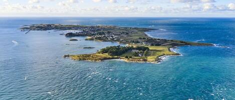 An aerial view of a coastal area with multiple islands, including a prominent island with a lighthouse and a cluster of buildings.