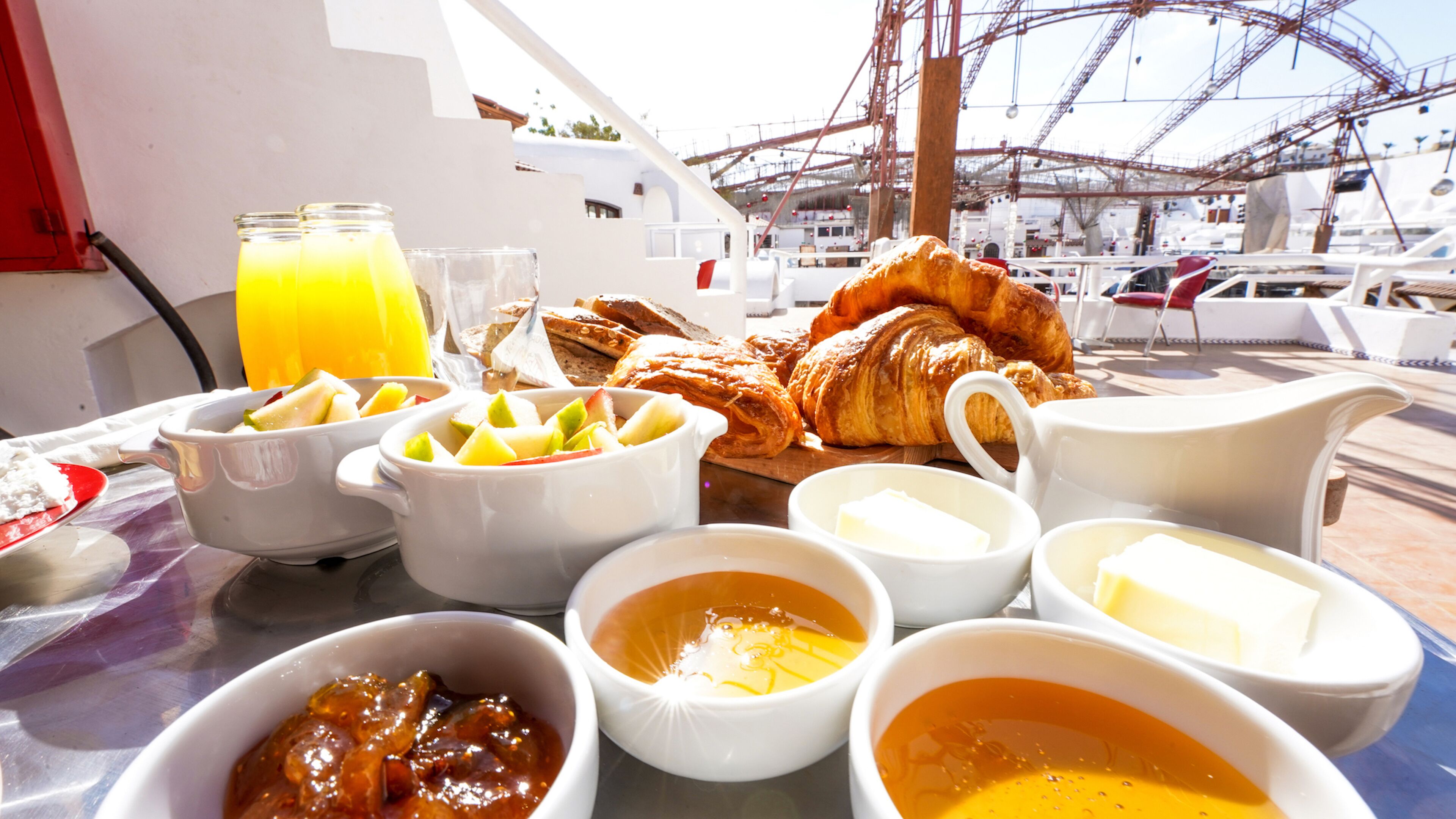A breakfast table with croissants, fruit, and various condiments.