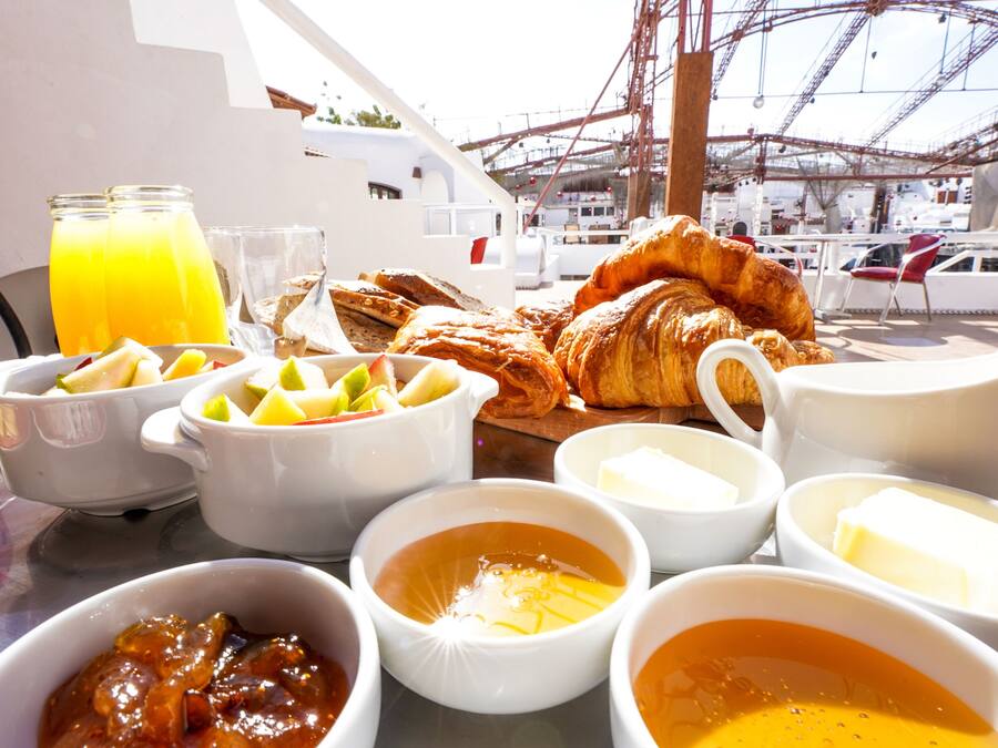 A breakfast table with croissants, fruit, and various condiments.