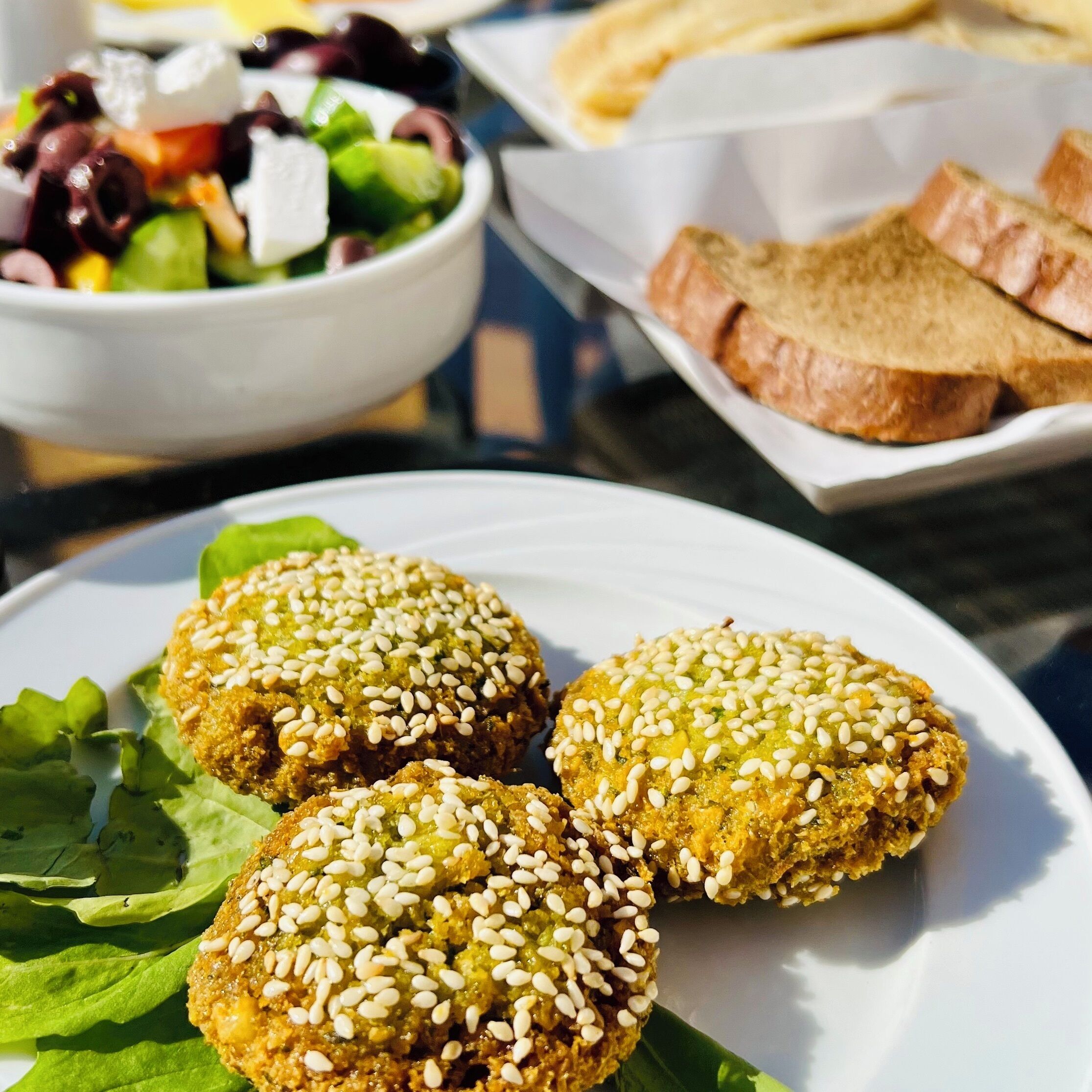 A plate of food with sesame seeds, a salad, and bread on a table.