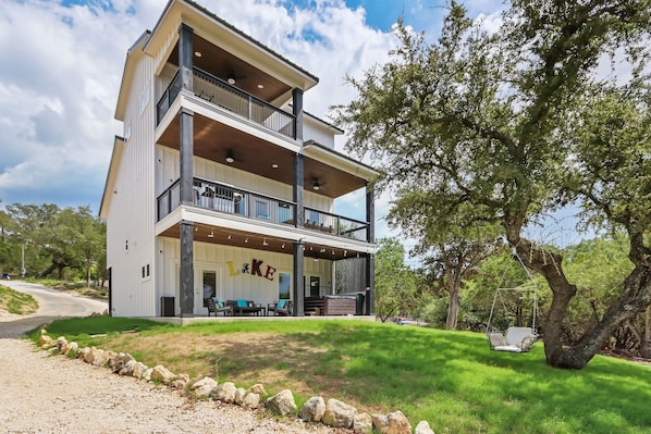 A multi-story building with a balcony, outdoor seating, and a hanging chair.