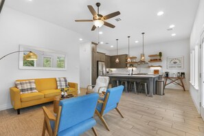 A modern kitchen with a central island, overhead lighting, and a ceiling fan.