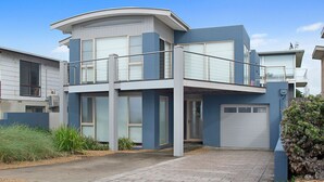 Een modern huis met twee verdiepingen, een plat dak, grote ramen en een garage.