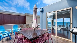 Enjoy al fresco dining on the deck with a scenic view of the water, featuring a grill and comfortable seating.