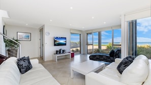 Relax in this stylish living room with a large flat-screen TV, comfortable sofa, and scenic ocean views from the balcony.
