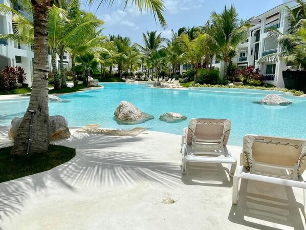 A pool area with lounge chairs, palm trees, and a clear blue pool.