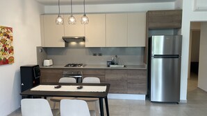 A modern kitchen with a dining area, stainless steel appliances, and a decorative wall piece.