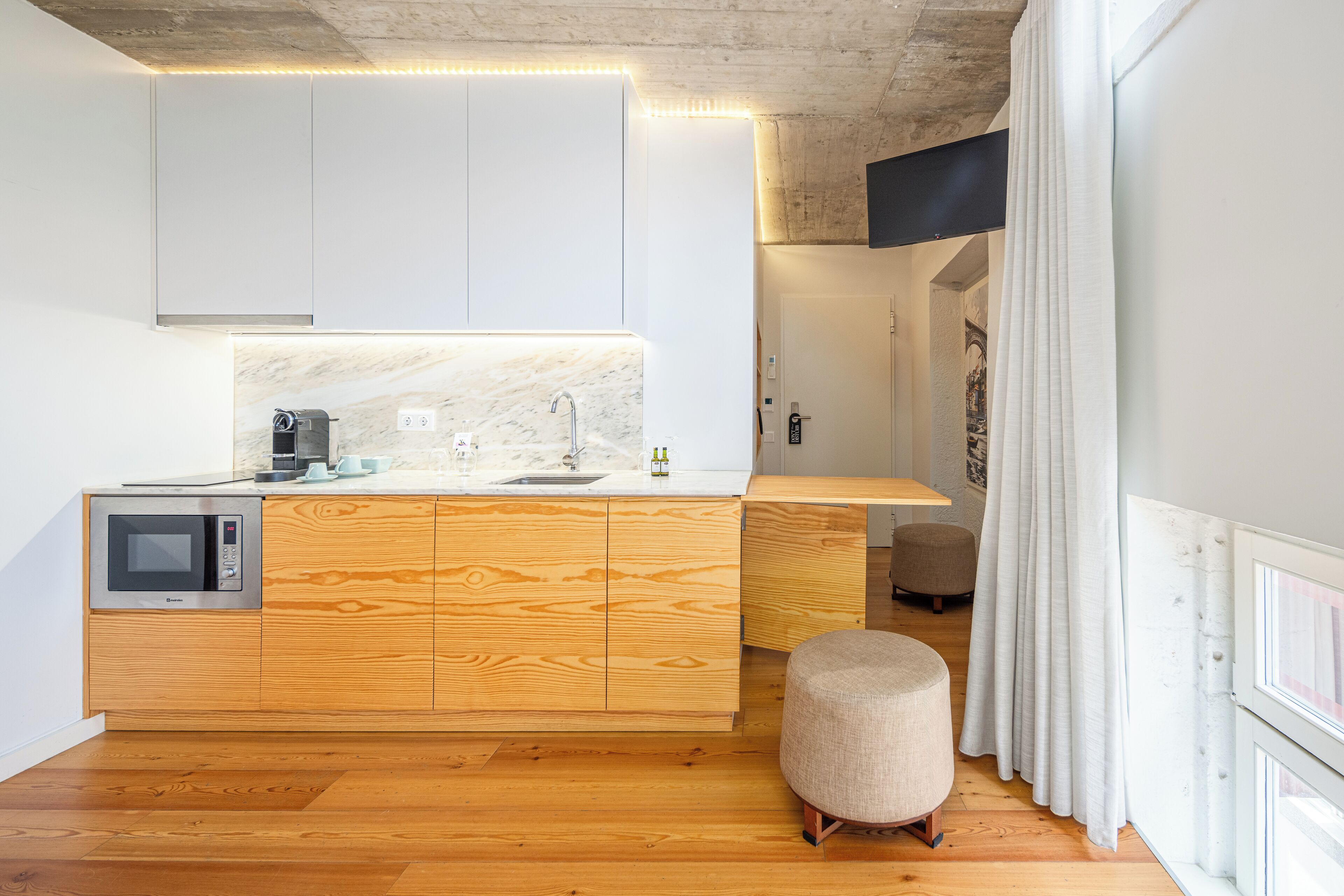 Una cocina moderna con una isla de madera, microondas integrado y salpicadero de mármol.