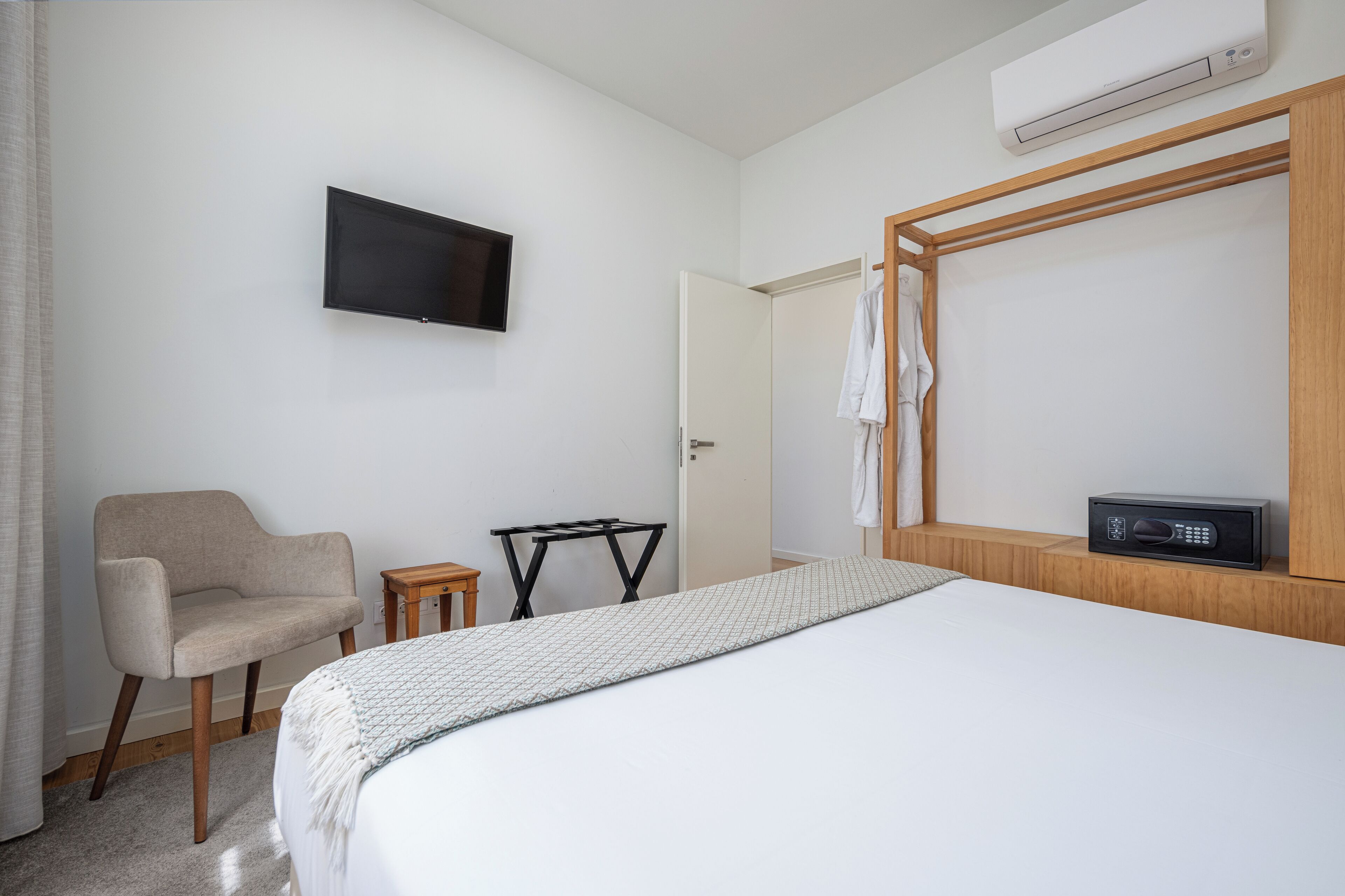 A hotel room with a bed, a chair, a small table, a TV, and a microwave.