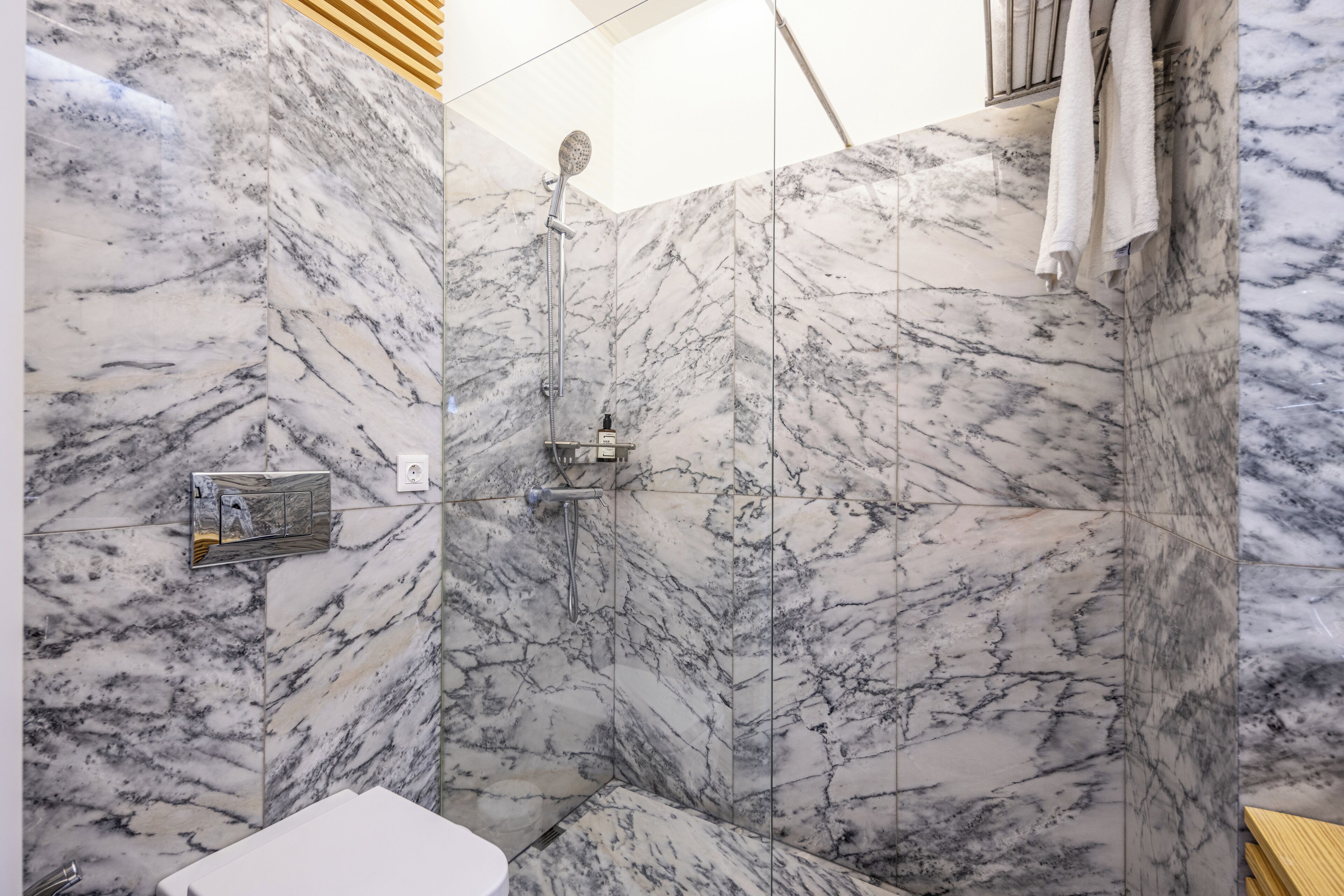 Une salle de bain avec des murs en marbre et un espace douche.