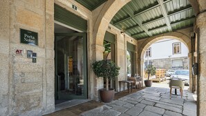 A stone building with a sign reading "Porta Nobre," a covered outdoor seating area with tables and chairs, and a potted plant. - Porta Nobre Boutique Hotel by Aspasios (Porto)