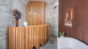 A reception desk with a wooden finish, a vase with flowers, and a sign reading "PORTA NOBRE." - Porta Nobre Boutique Hotel by Aspasios (Porto)
