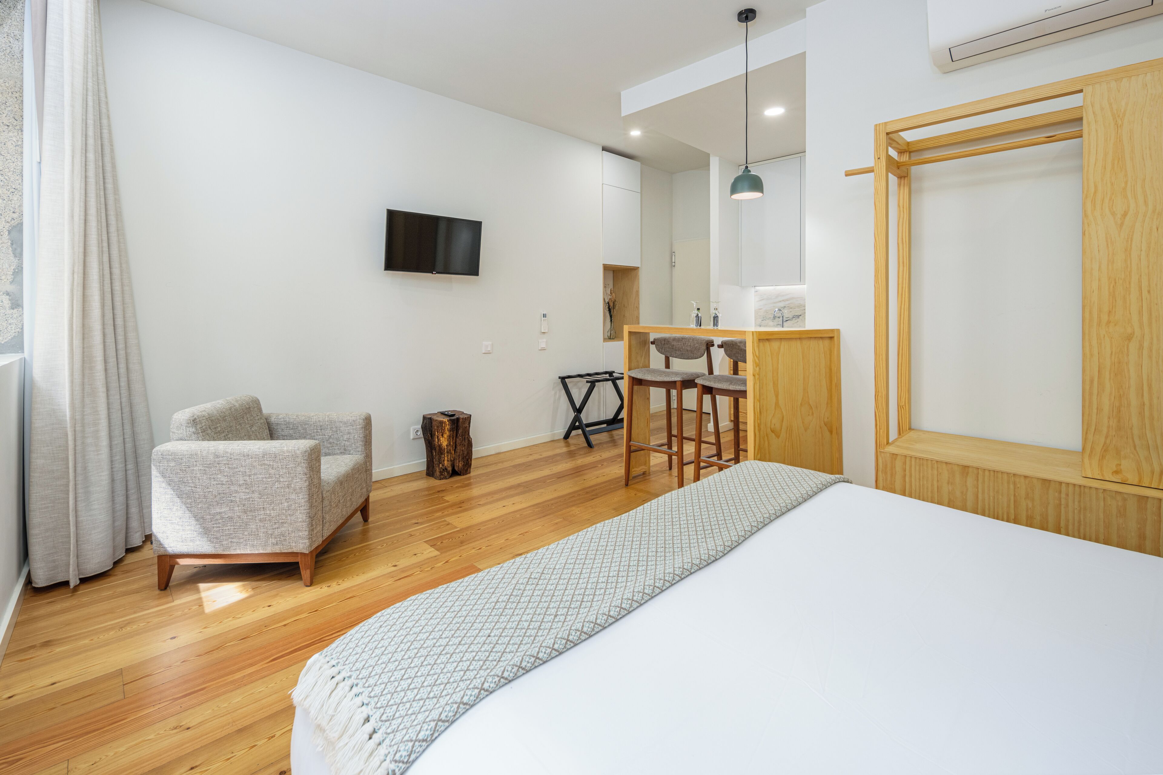 Une chambre à coucher moderne avec un lit, une chaise, un bureau et un téléviseur fixé au mur.