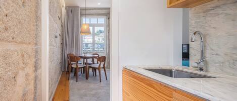 A compact kitchen with a wooden cabinet, a marble countertop, and a window with curtains.