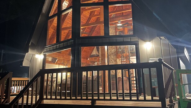 Een houten hut met een opvallend driehoekig dak en een balkon.